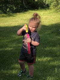 Full length of boy holding sunglasses on field