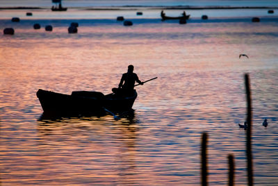 Silhouette man in boat at sea