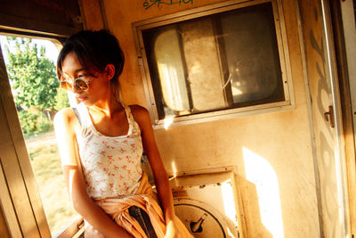 Young woman looking through window