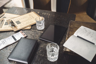 High angle view of drinking glass with diary and digital tablet on table in restaurant