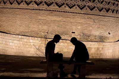 Silhouette couple sitting on bench