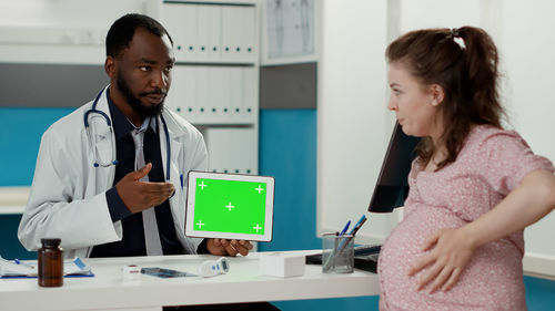 Doctor showing digital tablet to pregnant woman
