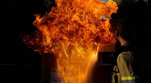 Firefighter standing against fire