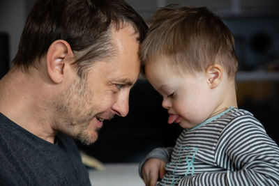 Side view of happy mid adult man looking at son with down syndrome