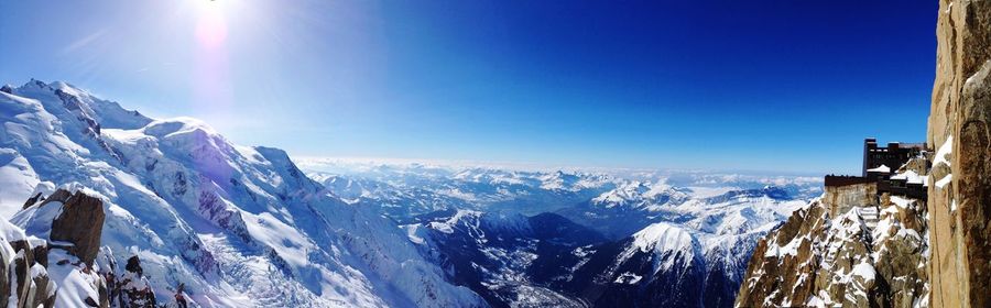 Scenic view of snow covered mountains against blue sky