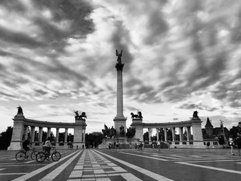 People at town square against cloudy sky