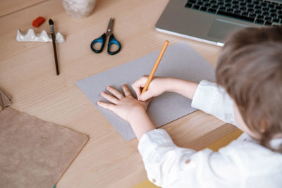 Child trace around a hand on paper with pencil using video lesson for drawing. distance education