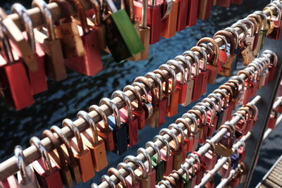 Multi colored padlocks hanging on railing at bridge