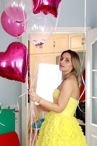 Happy girl with elegant yellow dress and balloons celebrating her bday