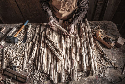 Midsection of man carving wood on table at workshop