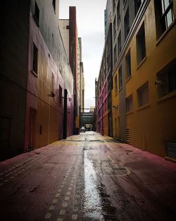 Empty wet alley amidst buildings during rainy season