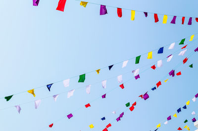 Low angle view of flags against clear blue sky