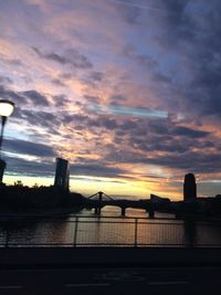 Silhouette of bridge over river at sunset