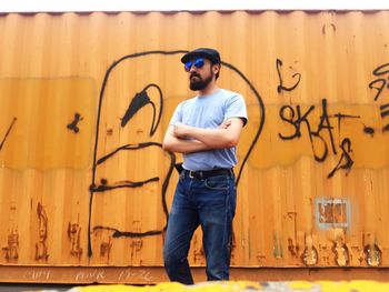 Man wearing sunglasses while standing against graffiti wall