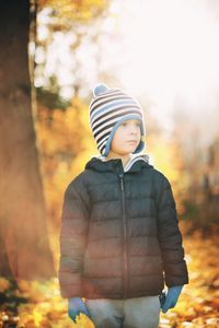 Boy looking away while standing on field during autumn