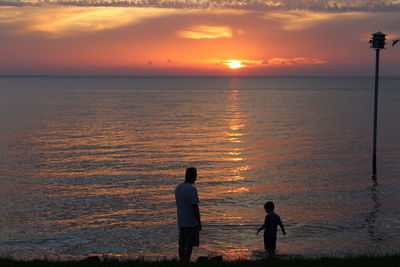 Silhouette of people in sea at sunset