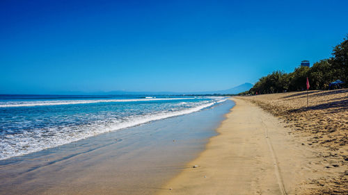 Scenic view of beach against clear blue sky