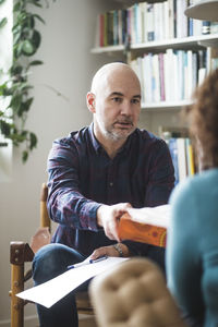 Male therapist giving tissue to female patient during therapy session