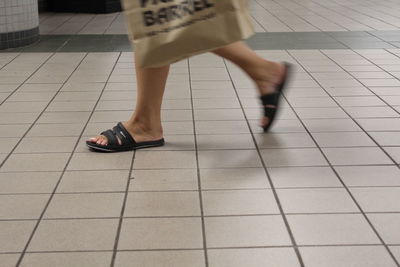 Low section of woman walking on tiled floor