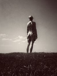 Rear view of woman standing on field against sky