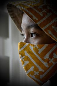 Close-up portrait of a serious young woman with mask at home