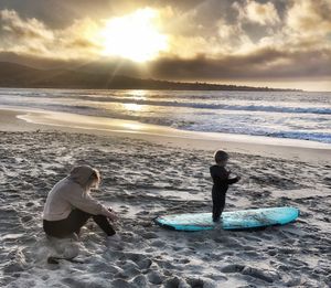 Boy on beach against sky during sunset