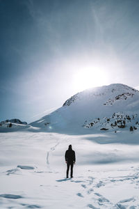 Rear view of person on snowcapped mountain against sky