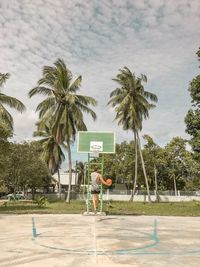 Rear view of man standing by palm trees against sky