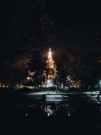 Illuminated city by street against sky at night