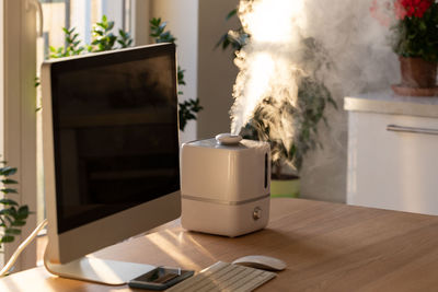 Aroma oil diffuser on table at home, steam from air humidifier. increase in air humidity indoors, 