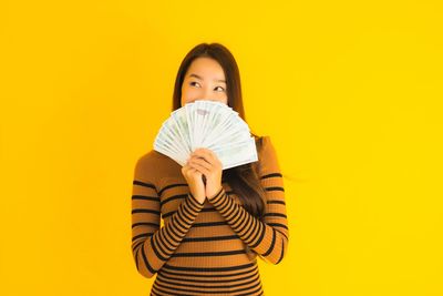 Portrait of beautiful woman standing against yellow background