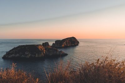 Rocks on sea against sky during sunset