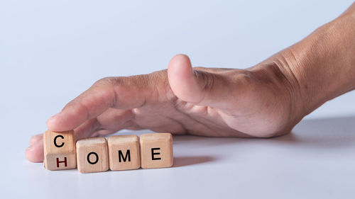 Cropped hand of person with toy blocks against white background