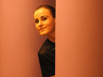 Portrait of smiling woman standing against orange wall