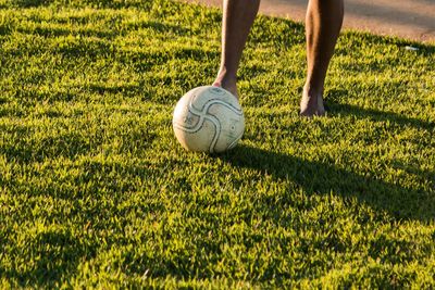 Low section of man playing soccer on field during sunny day