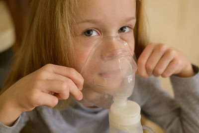 A sick child makes inhalation with a nebulizer at home, he holds a mask from which steam. the child