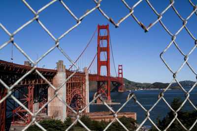 Bridge seen through chainlink fence against sky