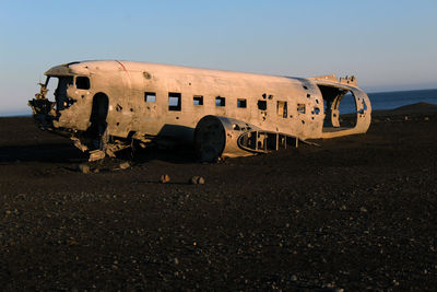Abandoned airplane on field against clear sky