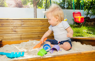 Portrait of boy playing with toy while sitting on swing at park