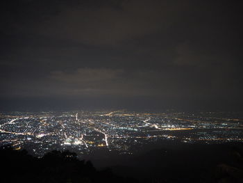 High angle view of illuminated city buildings against sky at night