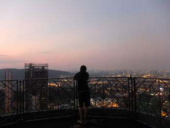 Silhouette of man standing on railing against sea