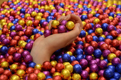 Human hand emerging from a deep pile of foil covered chocolate balls