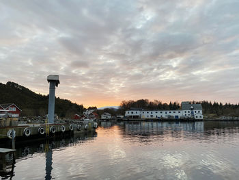 Reflection of buildings in lake against sky during sunset