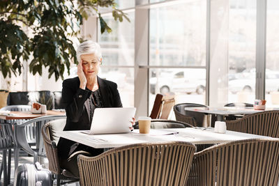 Woman using phone while sitting on table