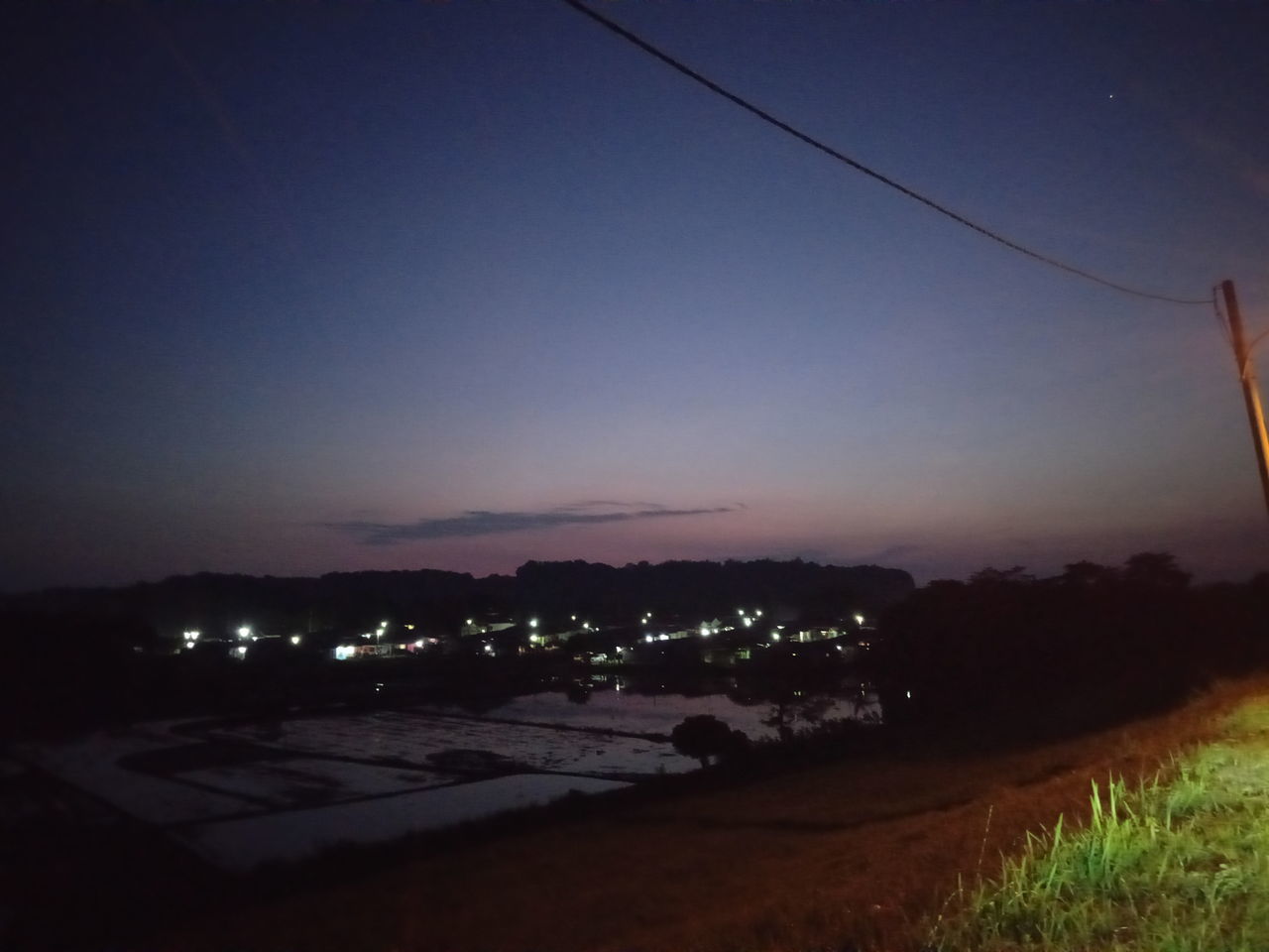 sky, night, dusk, evening, nature, light, horizon, no people, landscape, environment, illuminated, sunset, architecture, land, scenics - nature, plant, cloud, darkness, outdoors, beauty in nature, city, built structure, tranquility, electricity, field, building exterior, grass, tranquil scene