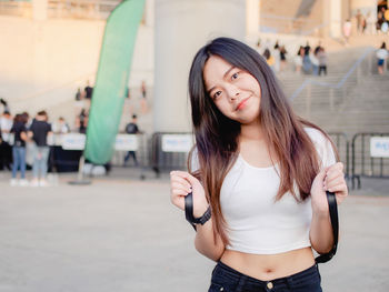 Portrait of young woman looking away while standing in city