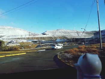 Road by snowcapped mountains against blue sky