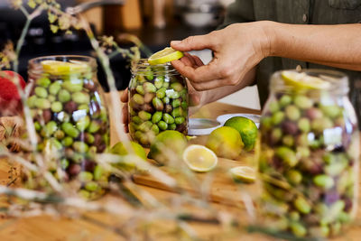 Woman prepares fermented olives in glass jars in the kitchen. autumn vegetables canning. 