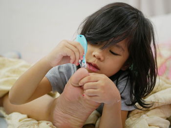 Cute girl looking away while relaxing on bed at home