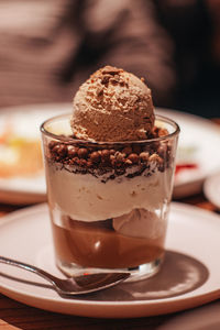 Delicious sweet chocolate ice cream in a transparent glass with chocolate chips and caramel cream